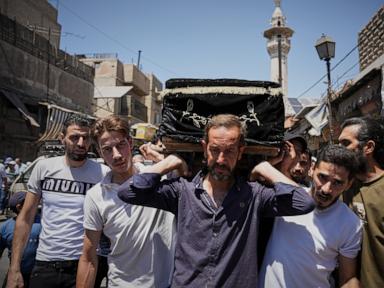 Source-feed image associated with Mourners in Damascus bury cafe blast victims as officials promise justice