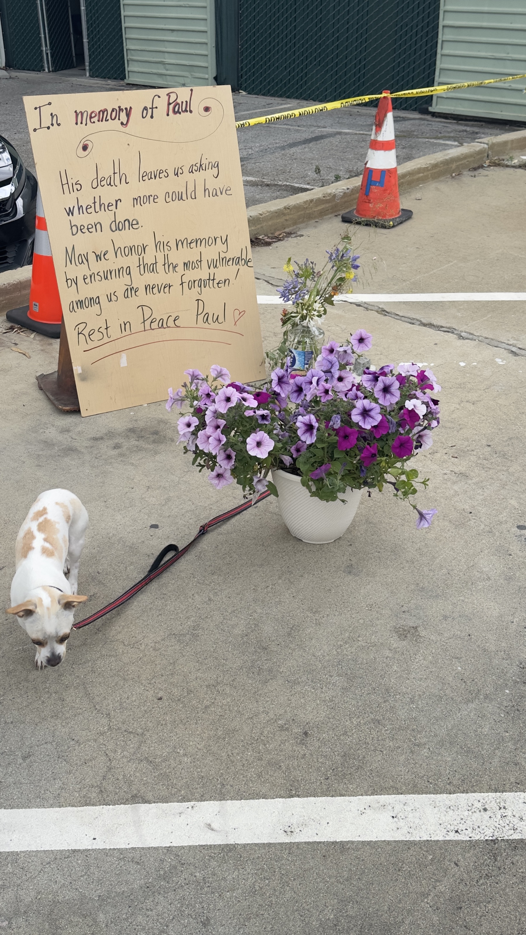 Memorial sign, flowers, and dog at the Geng safe-parking site